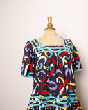 1990's Black Muumuu Midi dress with primary colored celebration confetti print and bell sleeves with pockets